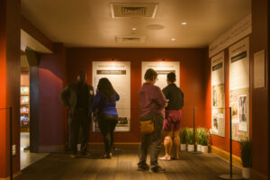 4 people stand in a hallway viewing an exhibit