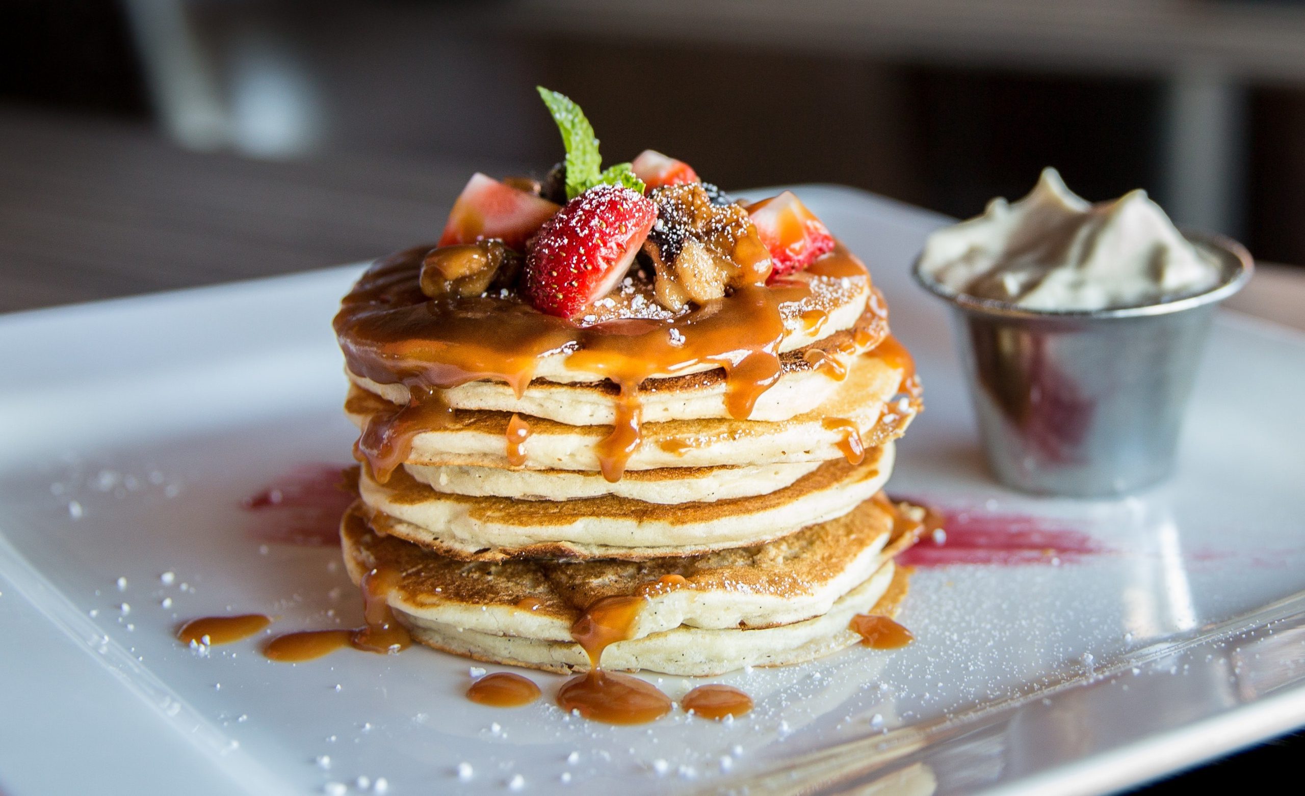A stack of pancakes covered in caramel with fresh fruit