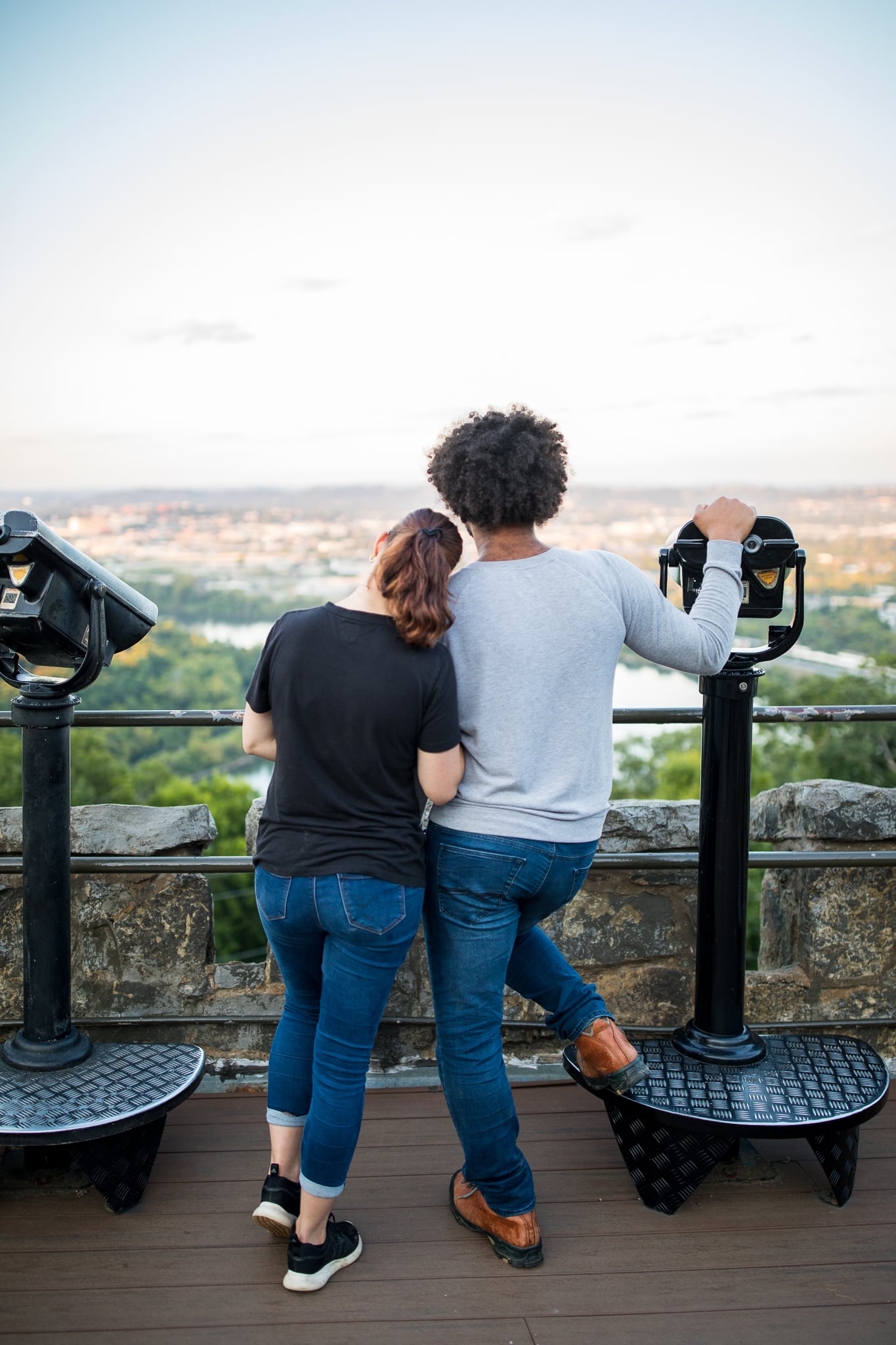A man and woman, shown from behind, look over a scenic overlook