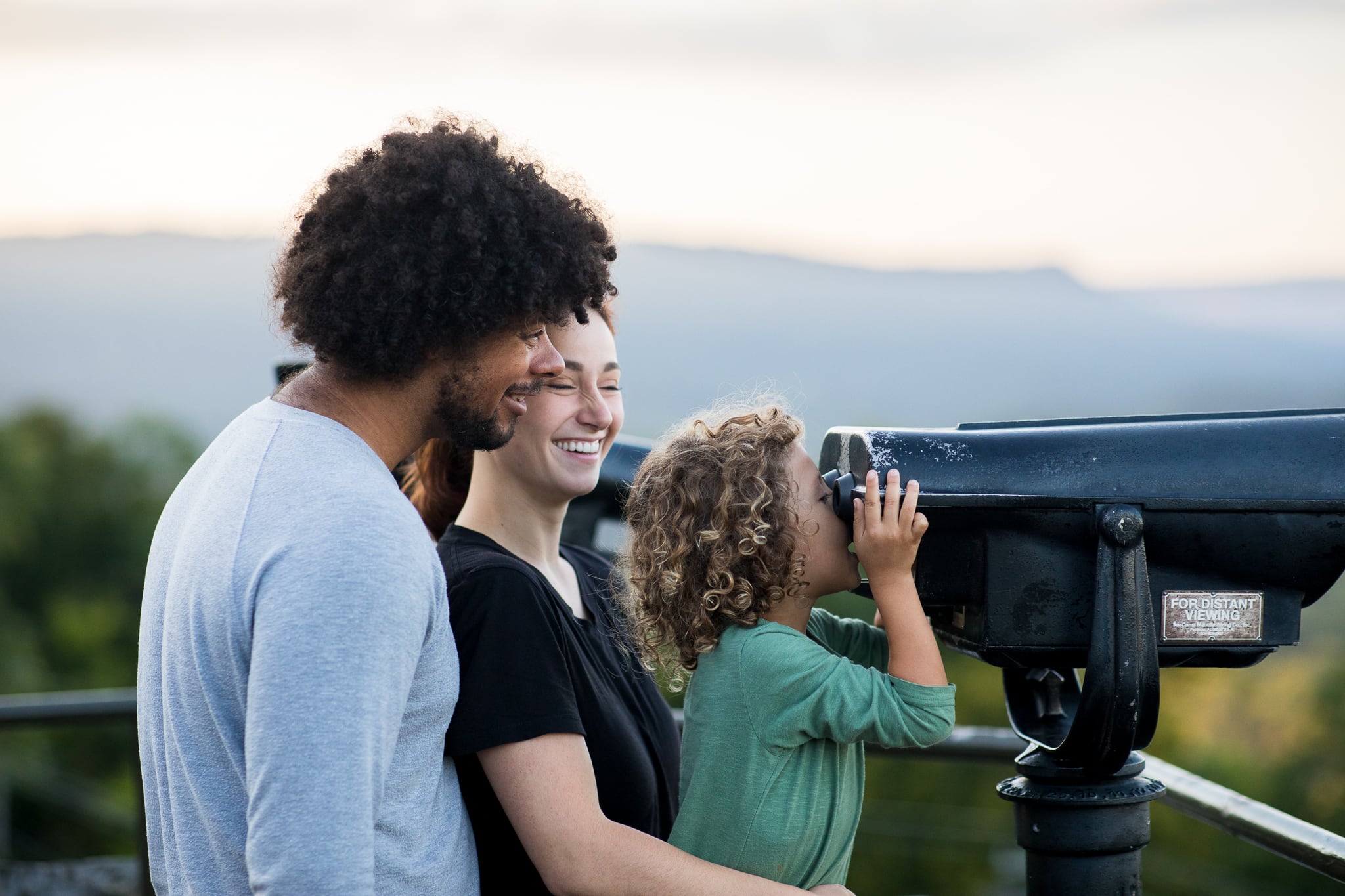 A man, woman and child look through a view finder