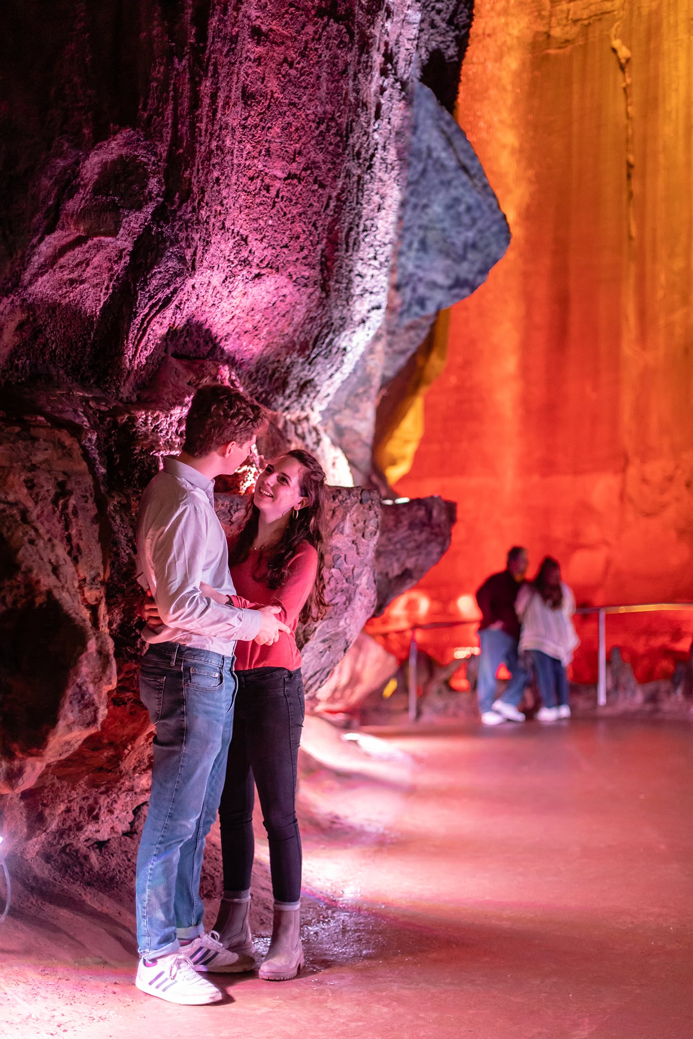 A young couple embraces in front of Ruby falls in the cave
