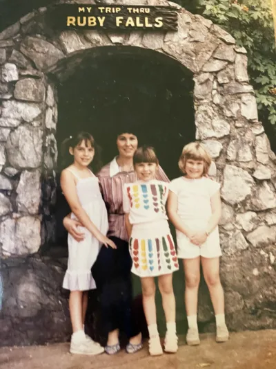 A 1980s-era photo of a woman and three girls in front of the Ruby Falls arch 