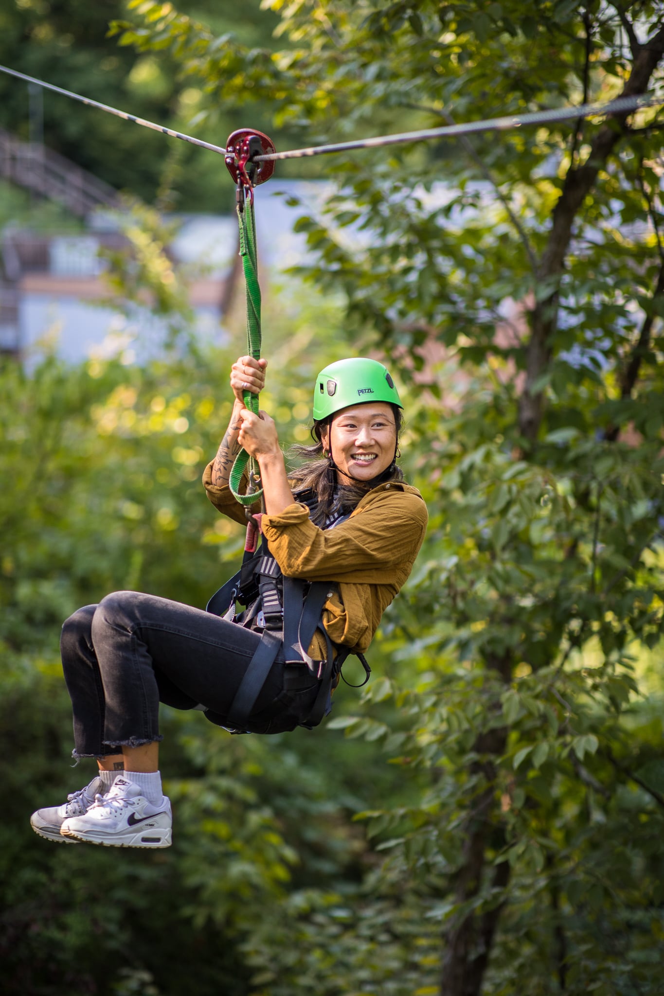 A woman rides a zipline through trees