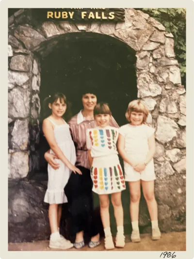 A 1980s-era photo of a woman and three girls in front of the Ruby Falls arch 