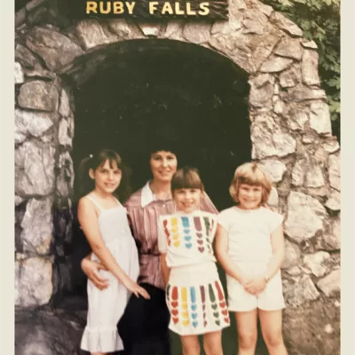 A 1980s-era photo of a woman and three girls in front of the Ruby Falls arch 
