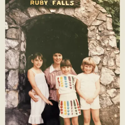 A 1980s-era photo of a woman and three girls in front of the Ruby Falls arch 