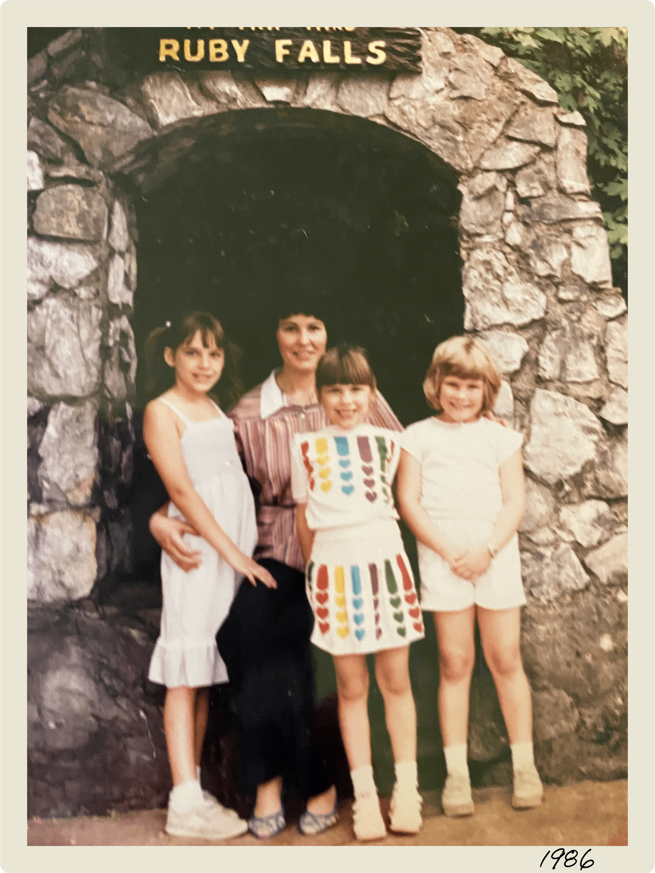 A 1980s-era photo of a woman and three girls in front of the Ruby Falls arch