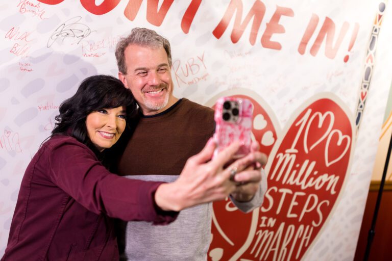 Couple taking a selfie in front of the 100 million steps banner