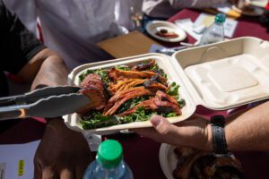 Someone grabbing food from a tray with tongs