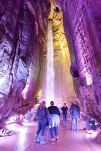 Group of people standing in front of a waterfall inside a cave.