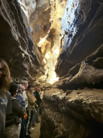 A small group of people stand inside Ruby Falls Cave, looking up towards the stalactites and drapery formations overhead. 